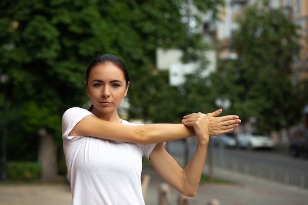 Ragazza abbastanza sportiva che fa le mani che si allungano al parco cittadino. Spazio per il testo