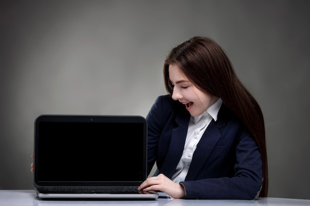 Ragazza abbastanza teenager che si siede al tavolo con il laptopSurfing the NET