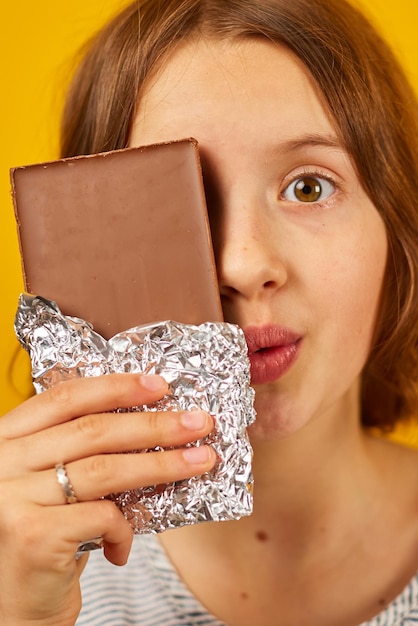 Ragazza abbastanza teenager con un fronte della copertura della barretta di cioccolato