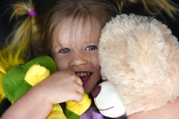 Ragazza abbraccia giocattoli di peluche e ride