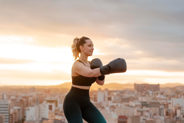 Ragazza adatta con i guantoni da boxe all'aperto