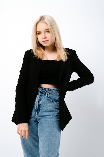 Ragazza adolescente alla moda in jeans larghi e giacca nera in posa