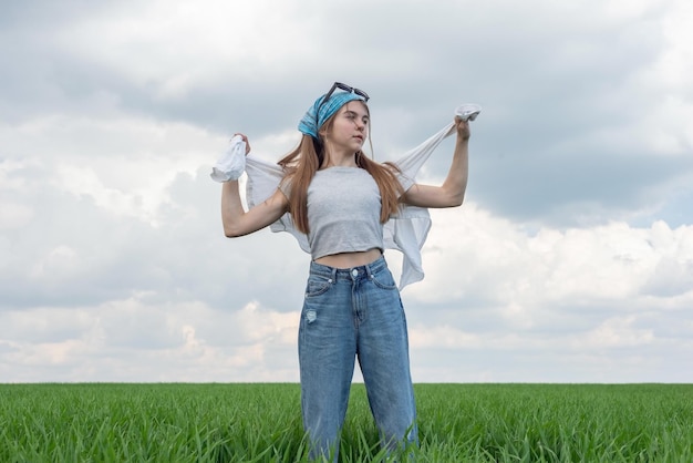 Ragazza adolescente alla moda in un campo di erba verde su uno sfondo di cielo nuvoloso