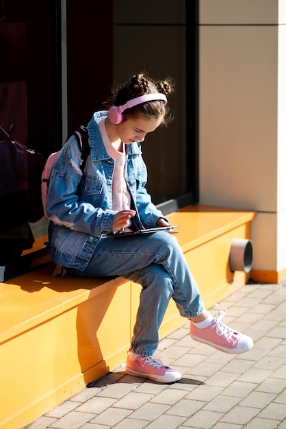 Ragazza adolescente carina con un gadget e cuffie Il concetto di gioventù moderna Bambini con gadget