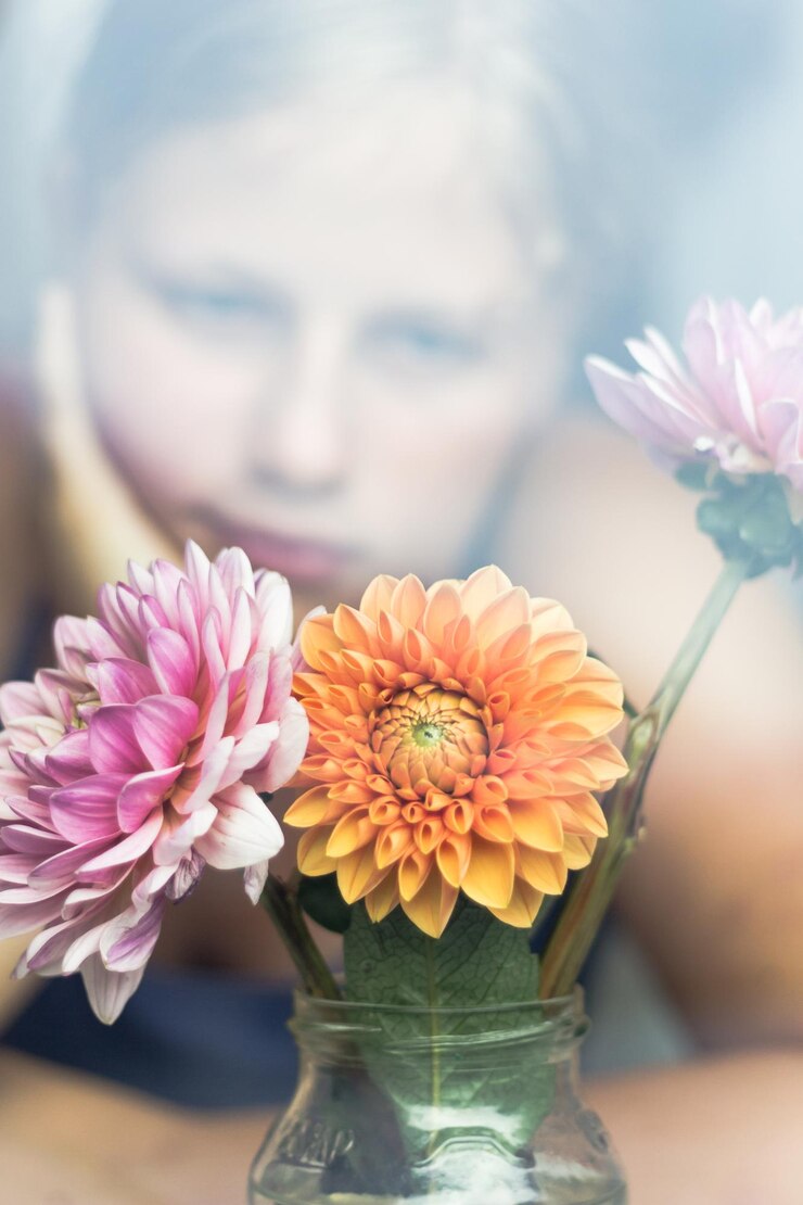 Foto ragazza adolescente che guarda i fiori visti attraverso una finestra di vetro