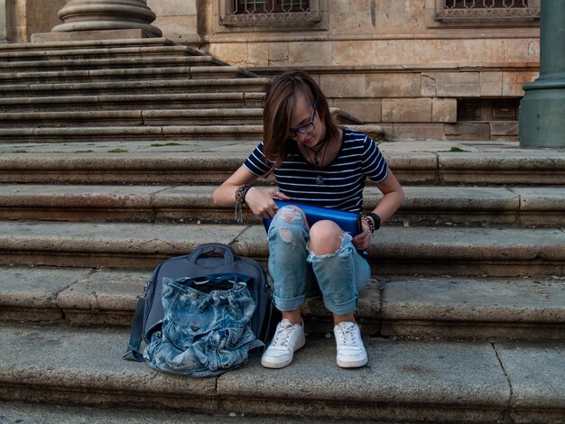 Ragazza adolescente che tiene in mano un file mentre è seduta sulle scale