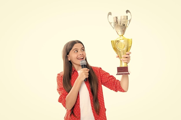 Ragazza adolescente che tiene un trofeo microfono discorso bambino vincitore bambino ha vinto la competizione festeggiando