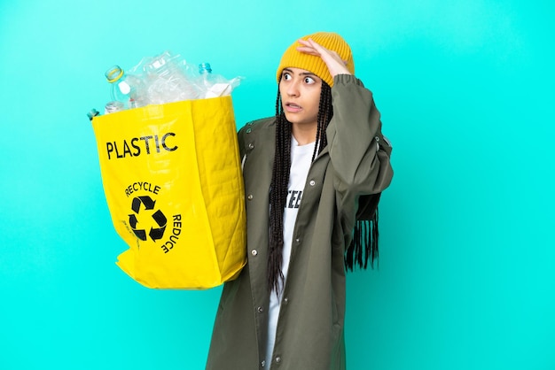 Ragazza adolescente con trecce che tiene una borsa da riciclare facendo un gesto a sorpresa mentre guarda di lato
