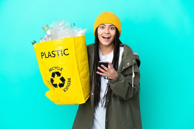 Ragazza adolescente con trecce che tiene una borsa da riciclare sorpresa e invia un messaggio