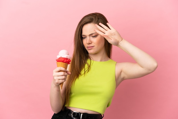 Ragazza adolescente con un gelato alla cornetta su sfondo rosa isolato che fa un gesto di arresto e deluso