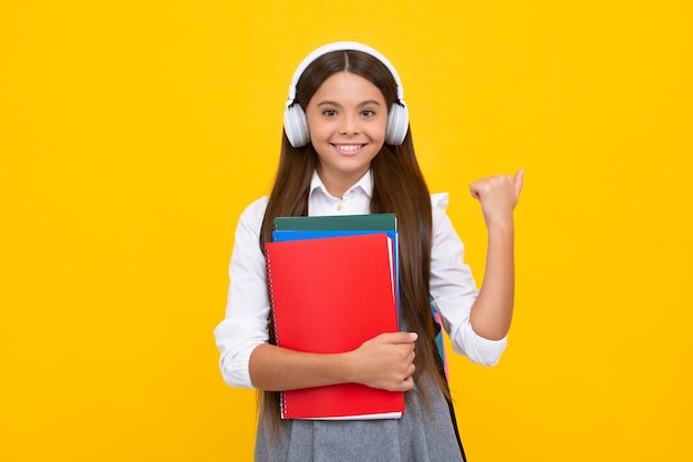 Ragazza adolescente della scuola in cuffie tenere quaderni di libri Ascolta musica Felice studentessa eccitata emozioni positive e sorridenti