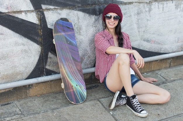 Ragazza adolescente divertendosi la sera d'estate all'aperto. Lei fa skateboard