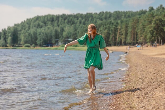 Ragazza adolescente felice che cammina lungo la costa Ragazza che gioca con l'acqua che spruzza sulla spiaggia durante le vacanze