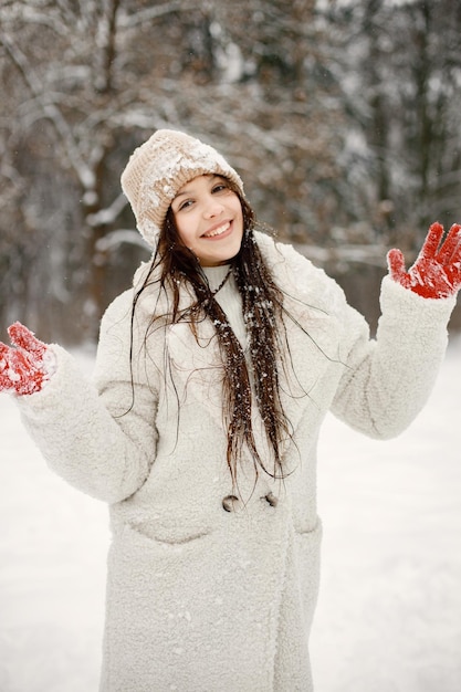 Ragazza adolescente in guanti rossi in piedi al parco invernale e in posa per una foto