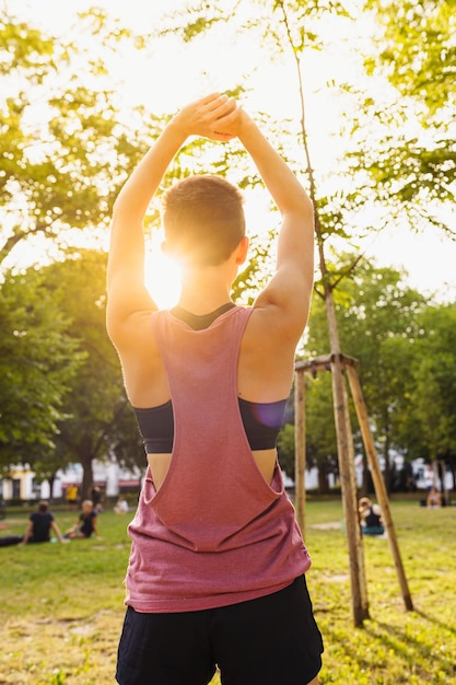 ragazza adolescente in pantaloncini sportivi e top fa allungare la schiena nel parco pubblico al sole. Attivo sano