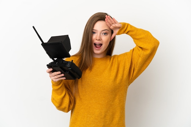 Ragazza adolescente in possesso di un telecomando drone su sfondo bianco isolato con espressione di sorpresa