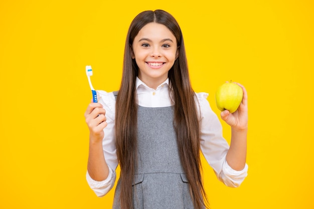 Ragazza adolescente lavarsi i denti su sfondo giallo isolato Vitamine mela per denti sani Igiene quotidiana teen bambino tenere spazzolino da denti routine mattutina Salute dentale igiene orale