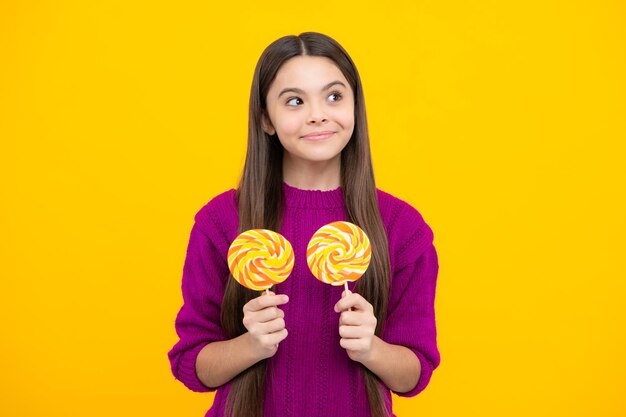 Ragazza adolescente mangiare lecca-lecca di zucchero caramelle e dolci per bambini Bambino mangiare ghiaccioli lecca-lecca su sfondo giallo isolato Yummy caramel candy shop