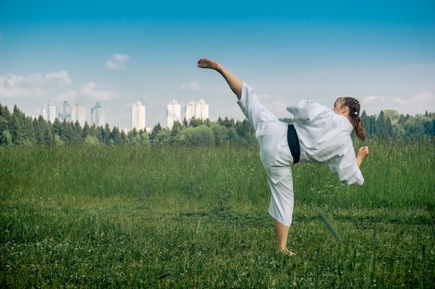 Ragazza adolescente praticando il karate kata all'aperto, esegue l'uro mawashi geri (hook kick)