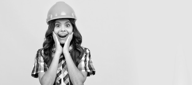 Ragazza adolescente sorpresa con i capelli ricci nel carpentiere del casco da costruzione Costruttore di bambini nel design del poster orizzontale del casco Spazio di copia dell'intestazione del banner