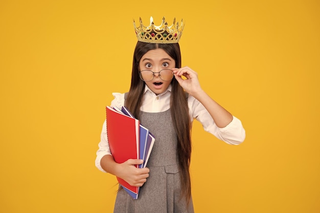 Ragazza adolescente sorpresa Studentessa in uniforme scolastica e corona che celebra la vittoria sul giallo