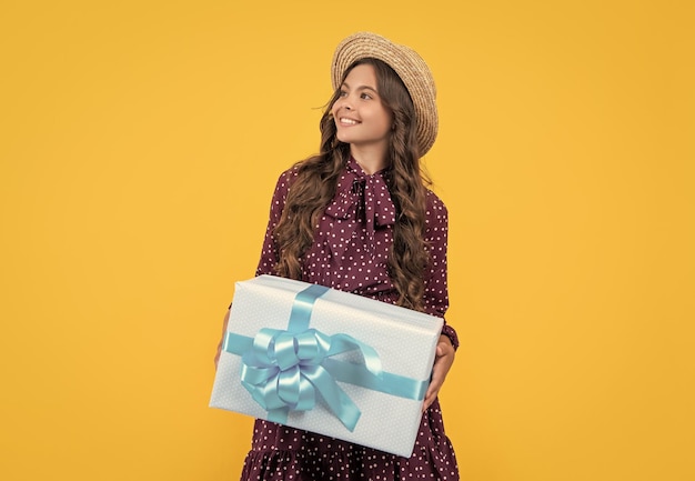 ragazza adolescente sorridente con una scatola di regali su sfondo giallo