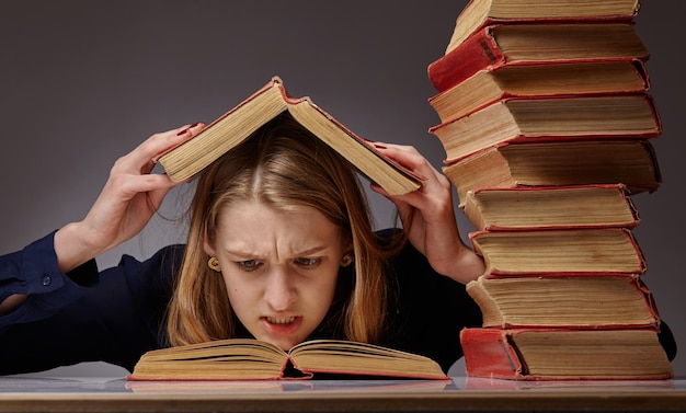 Ragazza adolescente stanca e annoiata sconvolta da un apprendimento difficile guardando la pila di libri stressata dalla preparazione del test d'esame, studente sopraffatto esausto con troppi compiti di studio, concetto di istruzione noioso