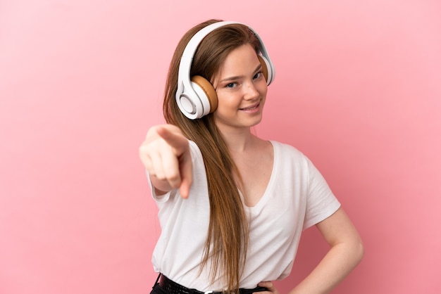 Ragazza adolescente su sfondo rosa isolato ascoltando musica