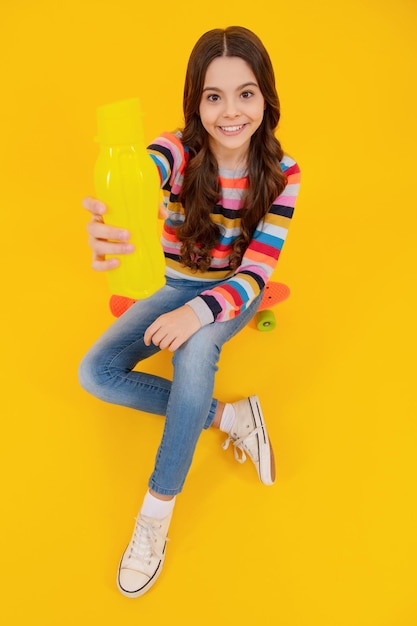 Ragazza adolescente tenere bottiglia d'acqua isolata su sfondo giallo Bottiglia d'acqua e vita sana Salute e equilibrio idrico Concetto di bevande e bevande Adolescente felice emozioni positive e sorridenti
