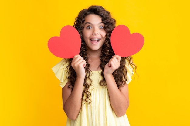 Ragazza adolescente tenere forma cuore heartshape segno Bambino che tiene un cuore rosso amore vacanze San Valentino simbolo Adolescente eccitato felice emozioni stupite e felicissime