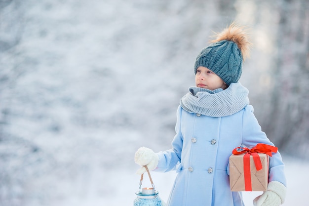 Ragazza adorabile con il regalo della scatola di natale in inverno all'aperto