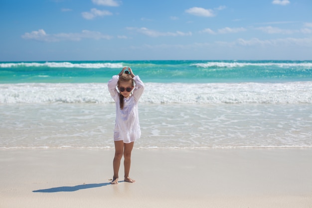 Ragazza adorabile del bambino in vestito bianco che cammina alla spiaggia esotica