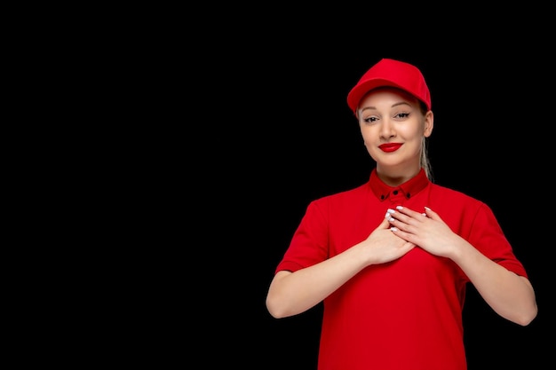 Ragazza adorabile del giorno della camicia rossa che tiene il petto in un berretto rosso che indossa una camicia e un rossetto brillante