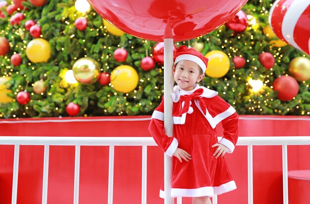 Ragazza adorabile del piccolo bambino in costume di Santa con il presente una priorità bassa di natale. Merry Xma