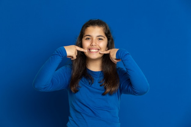 Ragazza adorabile del Preteen con la maglia blu che gesturing sopra la parete blu