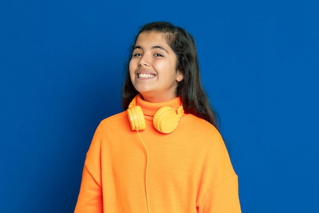 Ragazza adorabile del Preteen con la maglia gialla che gesturing sopra la parete blu