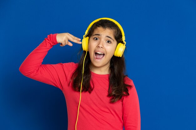 Ragazza adorabile del preteen con la maglia rossa che gesturing sopra la parete blu