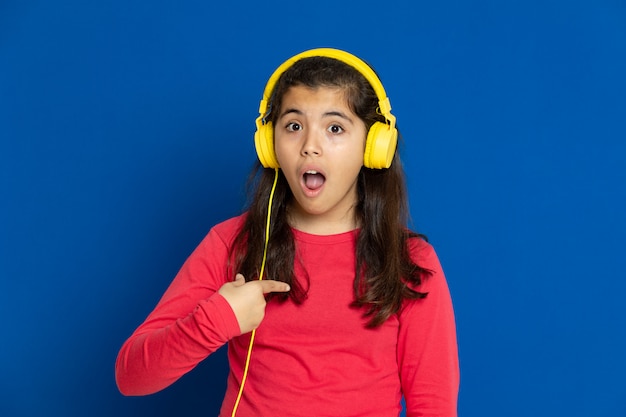 Ragazza adorabile del preteen con la maglia rossa che gesturing sopra la parete blu