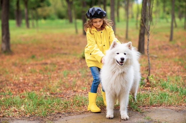 Ragazza adorabile su una passeggiata con un bello cane in un parco all'aperto