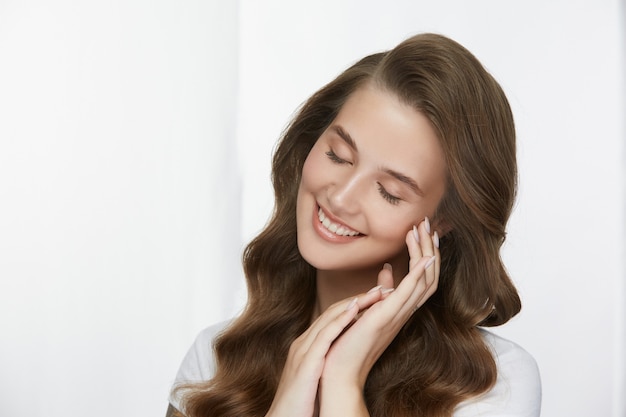 Ragazza adorabile sveglia con pelle fresca e capelli sani che sorridono sul bianco