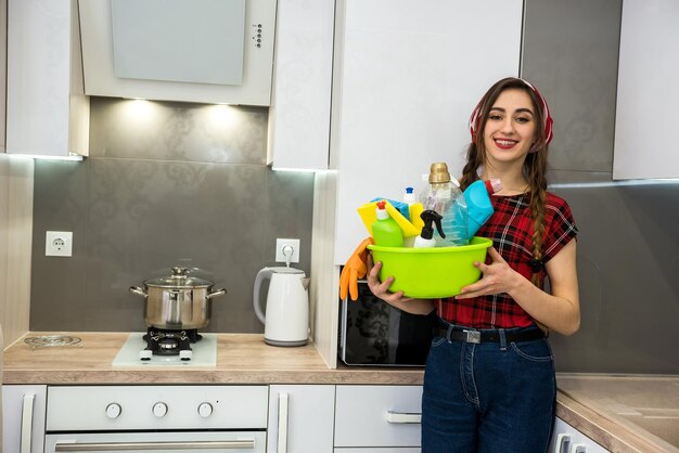 Ragazza adulta sorridente che pulisce la cucina con un flacone spray e un panno in microfibra