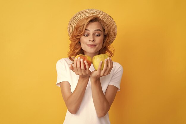 Ragazza affamata con vitamina mela frutta e donna a dieta con cappello di paglia che mangia cibo sano