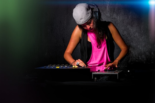 Ragazza affascinante deejay al lavoro che mescola il suono sulla sua console all'ap