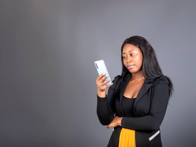 Ragazza africana che tiene guardando la chat di sms del telefono cellulare sul cellulare