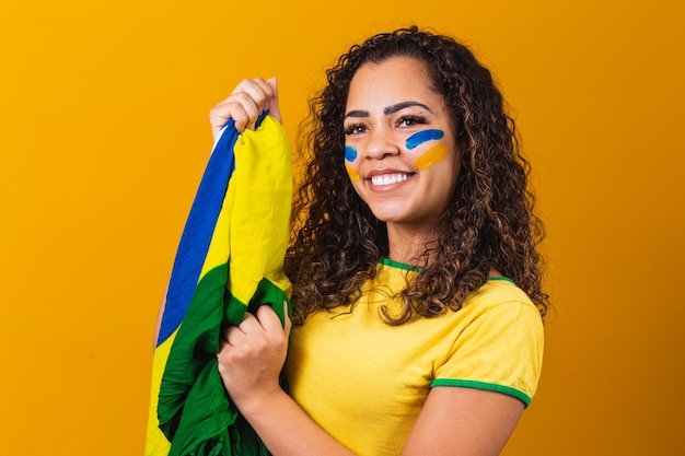 Ragazza afro tifo per la squadra brasiliana preferita, con bandiera nazionale su sfondo giallo.