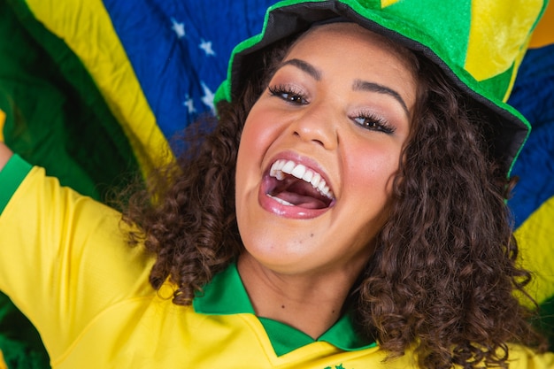 Ragazza afro tifo per la squadra brasiliana preferita, con bandiera nazionale su sfondo giallo.