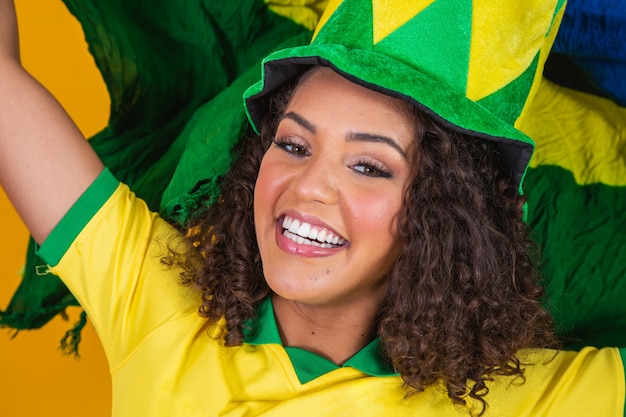 Ragazza afro tifo per la squadra brasiliana preferita, con bandiera nazionale su sfondo giallo.