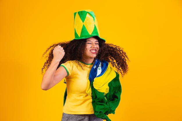 Ragazza afro tifo per la squadra brasiliana preferita, con bandiera nazionale su sfondo giallo.