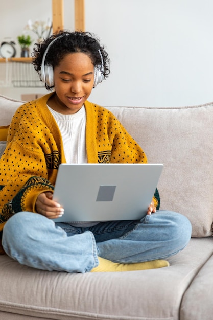 Ragazza afroamericana che usa il computer portatile in ufficio a casa guardando lo schermo digitando in chat leggendo la scrittura