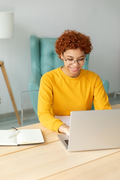 Ragazza afroamericana che utilizza il laptop in ufficio a casa guardando lo schermo digitando chattando leggendo scrivendo e-mail Giovane donna che ha una riunione virtuale chat online videochiamata conferenza Lavoro imparando da casa